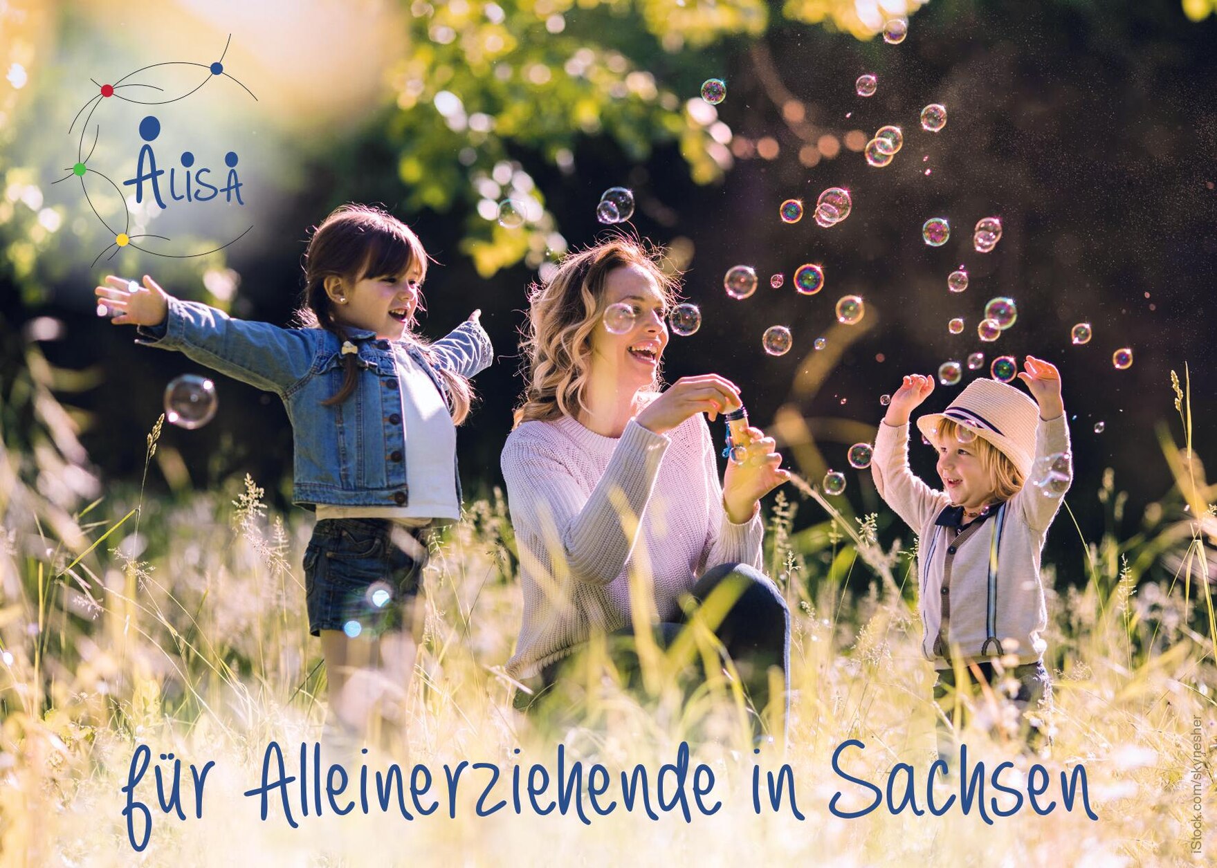 Alleinerziehende Mutter spielt mit ihren beiden Kindern auf einer Wiese. Die Kinder und die Mutter spielen mit Seifenblasen. Unter dem Bild steht für Alleinerziehende in Sachsen.